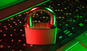 Brass padlock resting on a backlit computer keyboard, symbolizing network security and digital encryption.