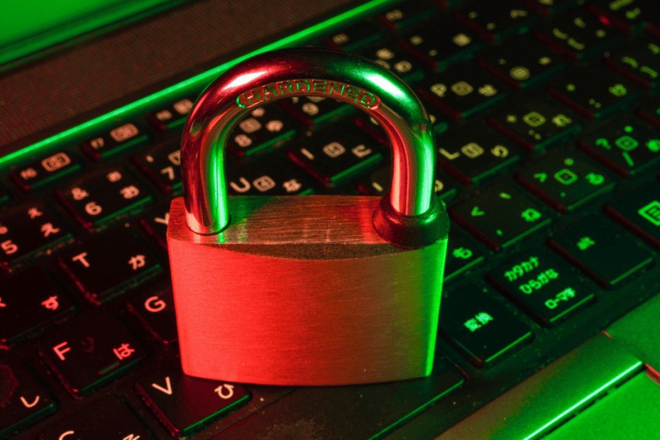 Brass padlock resting on a backlit computer keyboard, symbolizing network security and digital encryption.